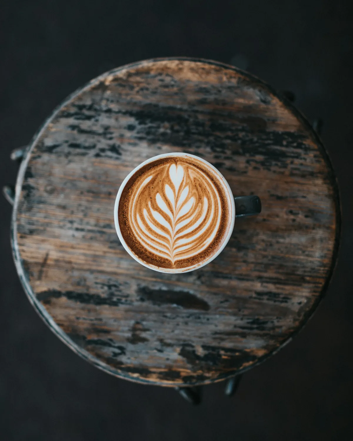 Taza de capuchino con arte latte sobre una mesa de madera